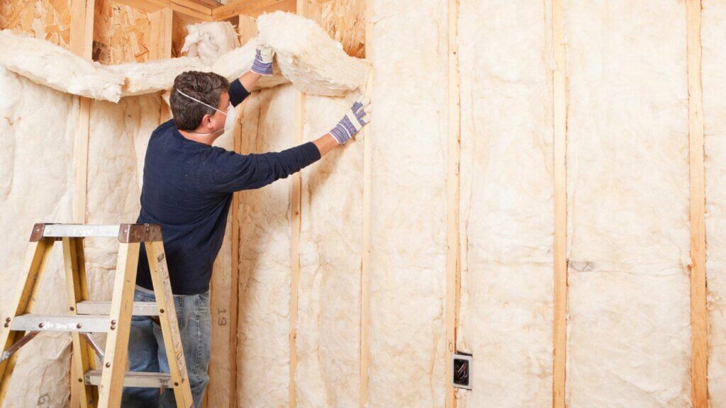 male worker installing insulation in a house